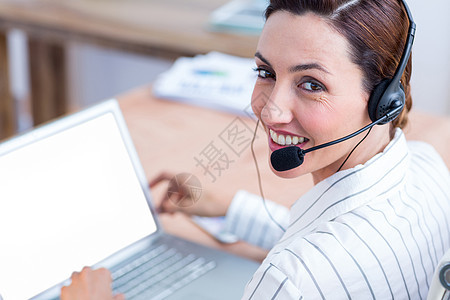 利用笔记本电脑和耳机微笑的棕发白脸色商业妇女办公室职业人士窗户技术商务女士快乐套装桌子图片