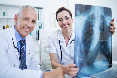 手持X光片 微笑着的医务同事的肖像保健从业者合作沟通桌子伙伴护士职业讨论x光图片