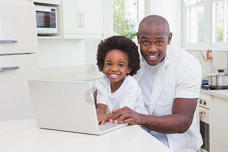 父亲和儿子在沙发上用笔记本电脑童年技术房子快乐孩子闲暇男性服装家庭生活男生图片