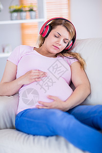 孕妇倾听音乐和抚摸肚子的女孕妇说谎长椅家庭分娩育儿沙发福利女性母亲家庭生活图片