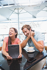 欢笑的年轻幸福夫妇滚动技术衬衫女性活动食品男性触摸屏行业混血图片