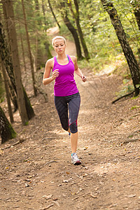 漂亮的年轻女孩在森林里跑步慢跑踪迹活动慢跑者赛跑者金发女郎火车公园女士越野图片