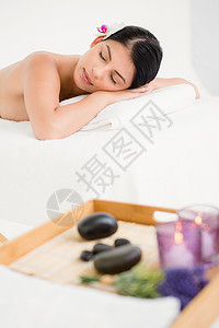 睡在按摩桌上的漂亮女人火焰生活方式热石睡眠身体棕色女性木头午睡水疗图片