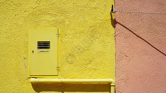 黄色墙上的金属管和电箱图片