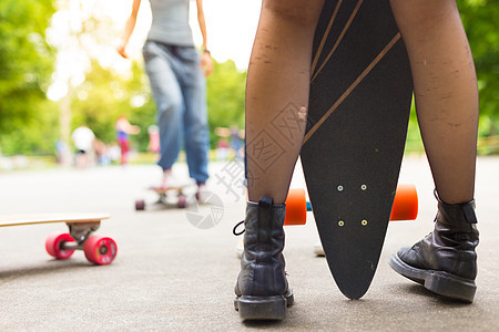 青少年女孩在城市骑长板车女性闲暇女士喜悦运动鞋青年溜冰者爱好滑冰太阳图片