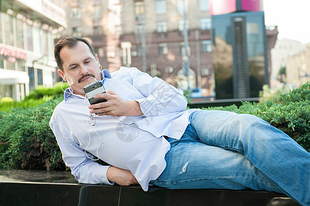 城市男子在外面使用智能电话使用4g无线dev的应用程序商业商务耳机人士网络金融学生音乐男人微笑图片