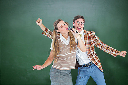 喜悦的嬉戏时装演员 用麦克风歌唱的复合图像黑板教育乐趣微笑金发女郎辫子衬衫头发计算机眼镜图片