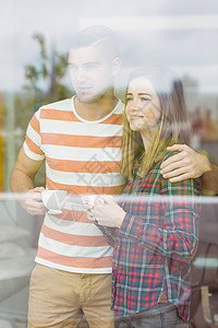 可爱的情侣向窗外看家庭生活窗户公寓闲暇感情杯子服装咖啡房子男性图片