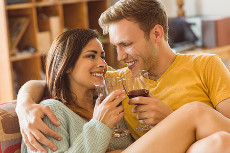 年轻夫妇用红酒抱在沙发上长椅女士酒瓶女朋友感情男性客厅拥抱家庭微笑图片