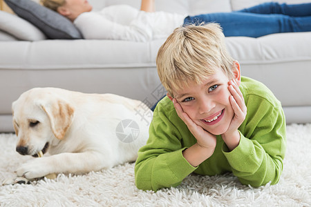 可爱的小男孩和他的小狗狗说谎闲暇客厅房子童年宠物沙发男性孩子快乐图片