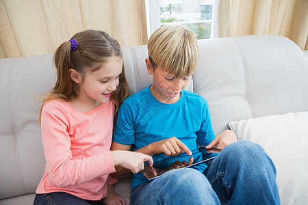 在沙发上使用平板电脑兄弟家庭生活滚动闲暇房子长椅家庭服装童年客厅图片
