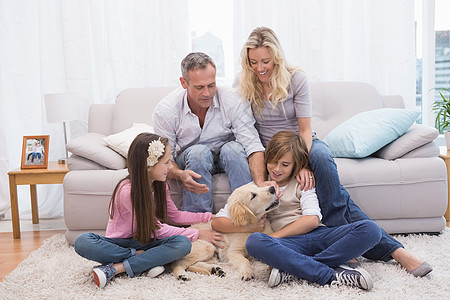 在地毯上带着宠爱的黄拉布拉多 微笑的家庭沙发客厅感情父亲女孩宠物小狗快乐女士头发图片