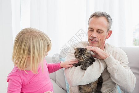 和宠物小猫一起坐在一起的快乐女儿和父亲家长头发男性女性孩子金发家庭生活长椅拥抱住所图片