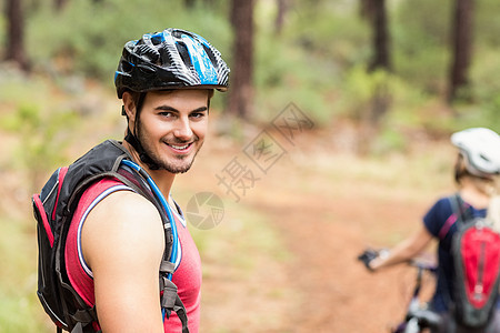 帅美的摩托车手看着镜头林地自行车头盔快乐越野夫妻手套男人女性冒险家图片