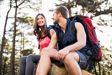年轻快乐的慢跑运动员坐在岩石上 向远看远足背包自由微笑女性闲暇农村冒险家男性男人图片