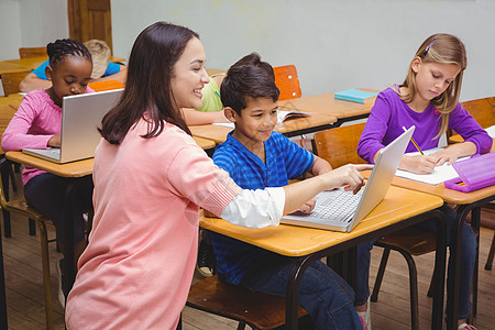 与学生一起使用笔记本电脑的快乐教师教学小学小学生课堂教育孩子帮助学校学习女孩图片