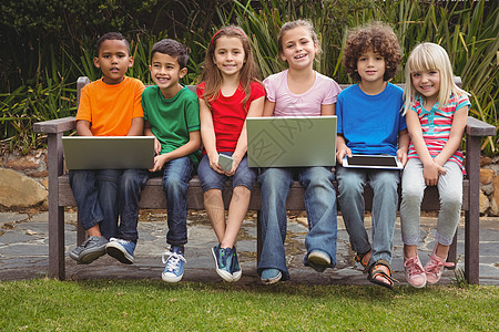 孩子们坐在公园长椅上手机瞳孔触摸屏笔记本男生快乐学校技术滚动早教图片