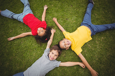 躺在草地上微笑的可爱学生绿色女孩快乐女性男生朋友教育小学生小学校园背景图片