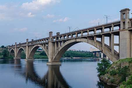 沿河的铁路和铁路两极分桥运输地标建筑学城市蓝色快手建筑支撑桥梁天空背景图片