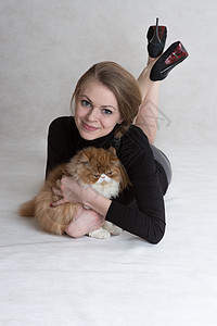 漂亮的女孩拿着一只红小猫亲热友谊宠物女性青少年拥抱肩膀混种乐趣哺乳动物图片