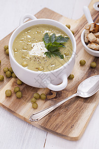 一个美味的豆奶油 配有木制桌子上的香味调味料白色奶油状午餐饮食绿色盘子勺子蔬菜食物美食图片
