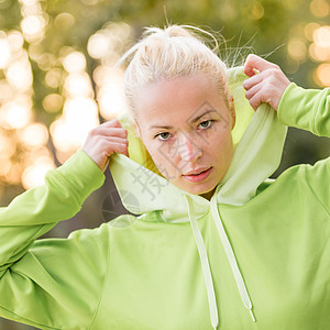 自信的体育女郎穿着时髦的绿色连帽衫头发活动金发女郎训练跑步慢跑者挑战兜帽女孩马尾辫图片
