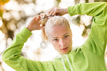 自信的体育女郎穿着时髦的绿色连帽衫马尾辫运动员公园跑步树木活动女性赛跑者挑战头发图片