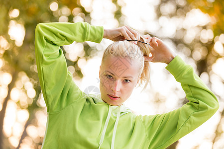 自信的体育女郎穿着时髦的绿色连帽衫头发成人运动马尾辫兜帽训练公园女士跑步娱乐图片