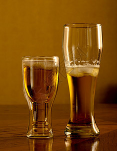 在木制桌子上用杯子装着光新啤酒图片