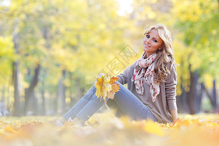 在秋天公园里坐着的女人森林微笑公园树叶金发叶子黄色女士女孩图片