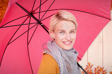 手持伞的微笑着的妇女的复合形象围巾栅栏木头金发女郎树叶帽子橙子金发快乐金子图片