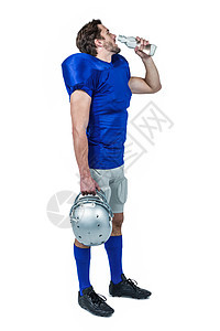 全长美式足球运动员在喝水时拿着头盔图片