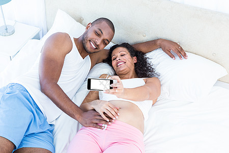 快乐的一对夫妇在睡觉时点击自拍图片