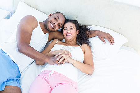 与丈夫躺在床上的幸福怀孕妻子的肖像图片