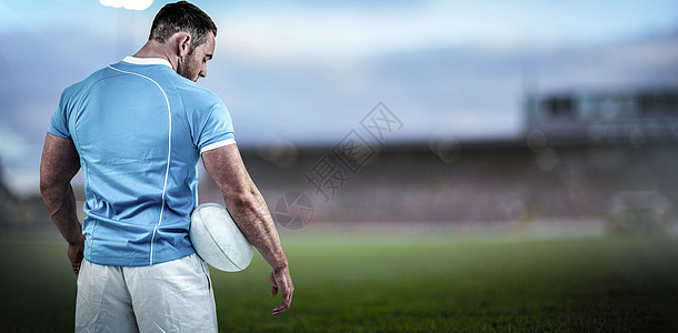 橄榄球运动员与球一起站立的复合图像男人服装运动服蓝色体育运动肌肉体育场绿色球衣图片