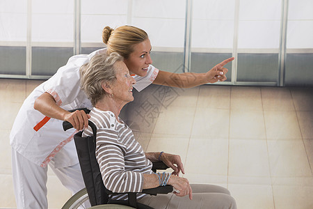 坐在轮椅上的老年妇女及其照顾者病人障碍退休草地居家护士护理荒地男性治疗师图片