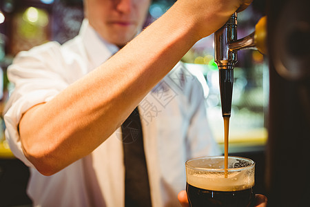 将啤酒杯握在喷洒器水龙头以下的男管家裁剪玻璃酒精酒吧酒保服务运动金属啤酒制服图片