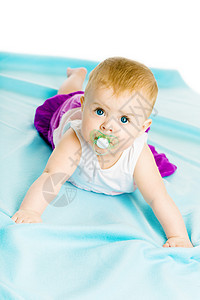 女婴 有奶嘴爬在蓝色的封面上图片