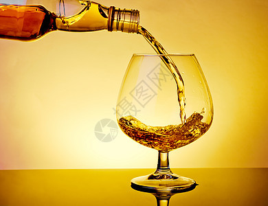 将白兰地喷洒在桌上的优雅典型白兰地杯子上气氛液体庆典派对食物麦芽金子饮料琥珀色玻璃图片
