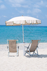 在雨伞下在沙滩上坐两张甲板椅游泳按摩蓝光防晒霜乐趣财富毛巾太阳浴室淋浴图片