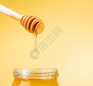 金色的蜂蜜罐头 上面有木制花朵和滴下来的蜂蜜液体花蜜玻璃甜点治愈早餐营养塞子饮食食物图片