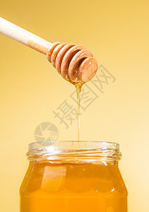 金底的蜂蜜罐头 顶上有木制蜂蜜加滴蜂蜜图片