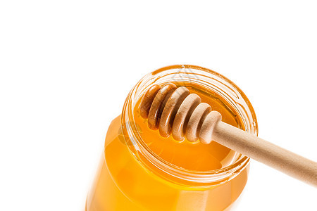 白色背景上的蜂蜜罐头的顶部视图 上面有木制蜂蜜薄饼图片