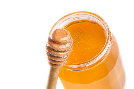白色背景的开口蜂蜜罐 在木制蜂蜜池边图片