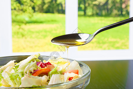 在意大利新鲜沙拉上加橄榄油的勺子香料小吃蔬菜盘子叶子食物餐厅果汁烹饪窗户图片