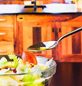 在意大利新鲜沙拉上加橄榄油的勺子 在木制厨房上加橄榄油和番茄美食午餐果汁餐厅叶子蔬菜营养柠檬烹饪桌子图片