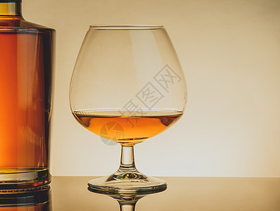 用优雅的典型白兰地杯子喝白兰地 放在桌边瓶子旁边 温暖风格图片