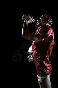 美国足球运动员身穿红球衣 在饮用水中戴头盔的复合形象四分卫体育运动红色竞技水壶头饰男人黑色男性图片