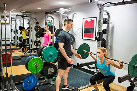合适的妇女把重担室的重型巴铃举起来锻炼力量男性身体健身房健身闲暇工作室男人运动图片