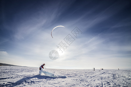 雪上放着蓝风筝的滑板机假期活动阳光天空追求男性冲浪旅行力量乐趣图片